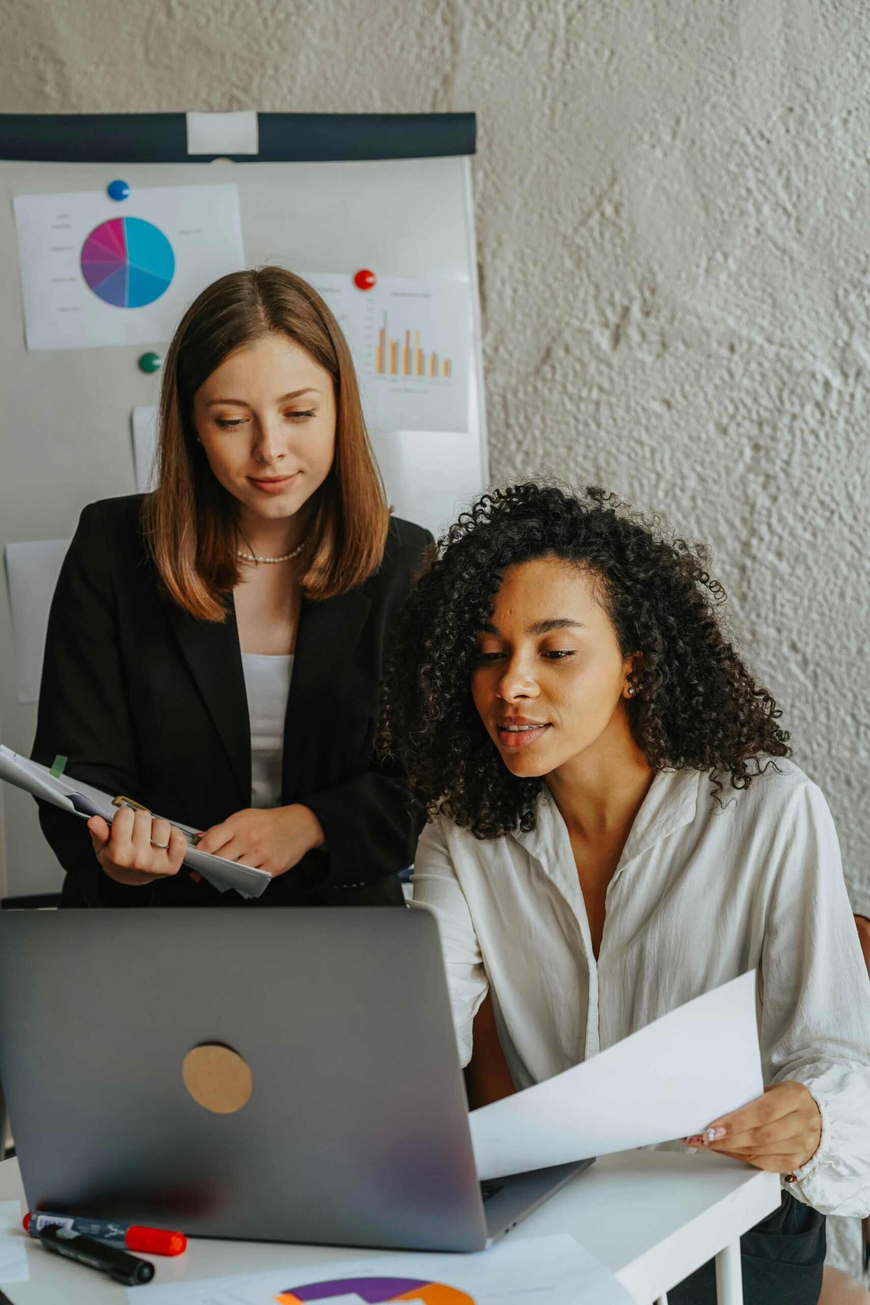 Two confident women working together on a project in a modern office.